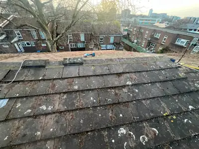 Completed tiled roof with the ridge tiles secured, overlooking a street of brick houses