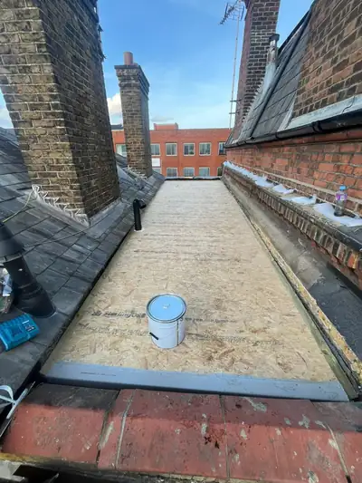 Prepared OSB flat roof deck between chimney stacks, with GRP trims fitted ready for coating