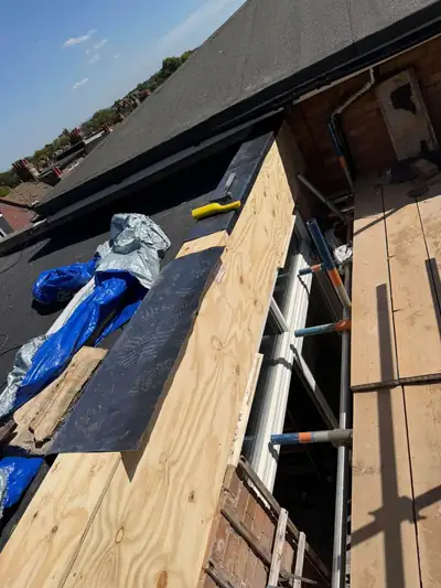 New lead flashing being formed along a newly clad timber roof edge from the scaffold