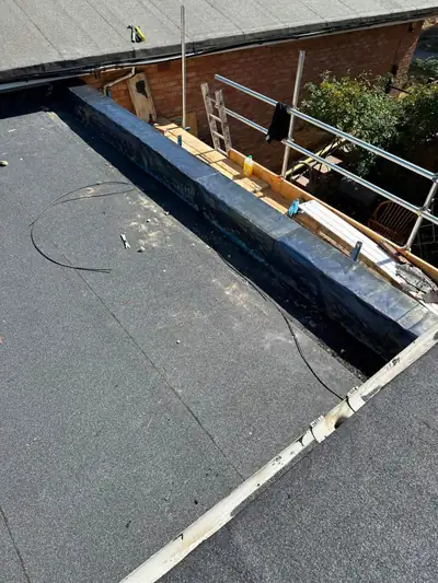 Finished leadwork and new flat roof covering along a rebuilt parapet, seen from above