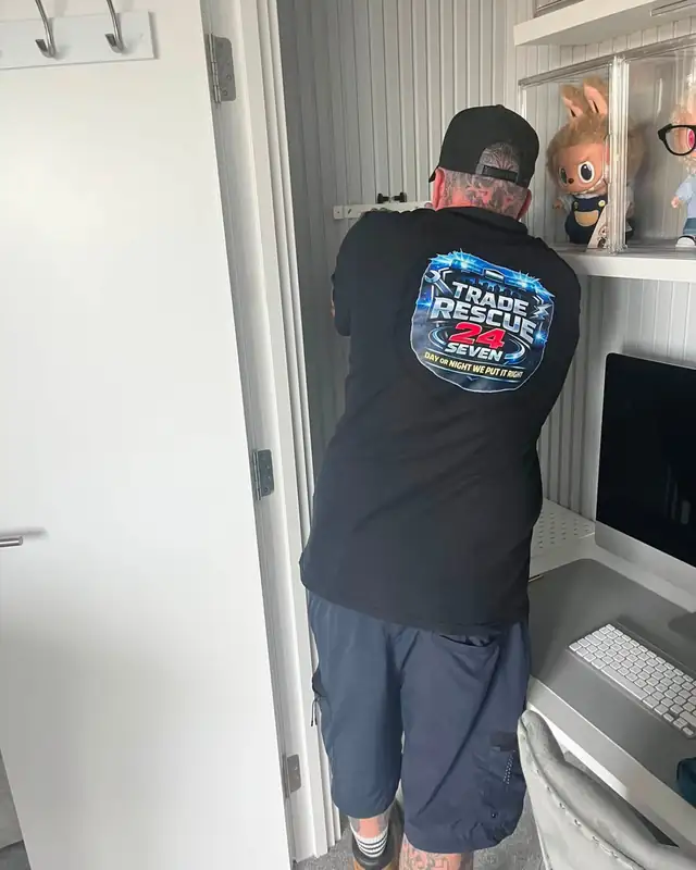 Trade Rescue 24/7 engineer at work indoors, wearing the firm’s branded black T-shirt and cap